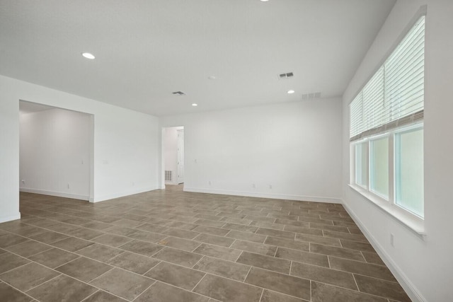 empty room with recessed lighting, visible vents, and baseboards