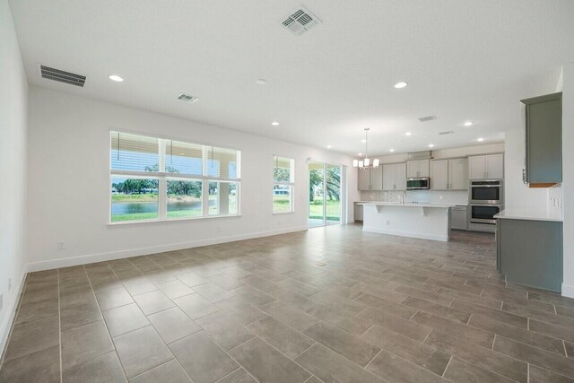 unfurnished living room with a notable chandelier, sink, and light tile patterned floors