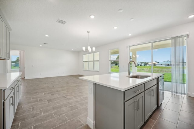 kitchen with gray cabinets, sink, light tile patterned floors, and a kitchen island with sink