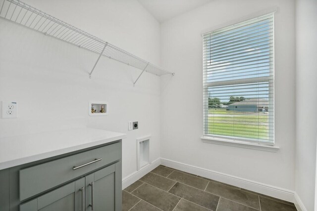 clothes washing area with cabinets, dark tile patterned floors, hookup for an electric dryer, and washer hookup