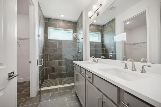 bathroom featuring a spacious closet, a stall shower, and a sink