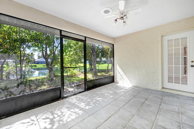 unfurnished sunroom with a water view and ceiling fan