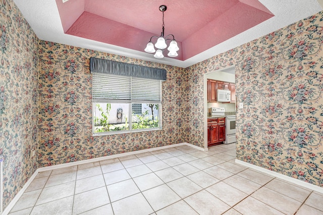 tiled spare room with a tray ceiling, a textured ceiling, and an inviting chandelier