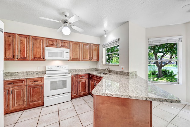 kitchen featuring white appliances, sink, light tile patterned floors, a textured ceiling, and kitchen peninsula