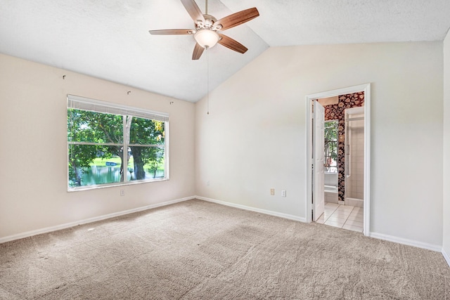 carpeted spare room with ceiling fan, a textured ceiling, and vaulted ceiling