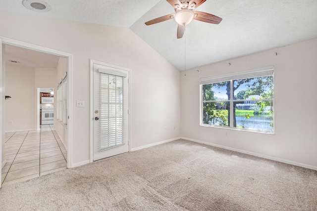 unfurnished room featuring a textured ceiling, ceiling fan, carpet floors, and vaulted ceiling