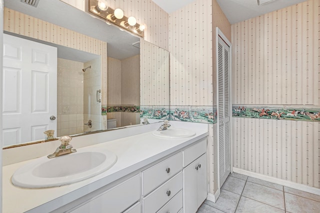 bathroom featuring tile patterned flooring, a tile shower, and vanity