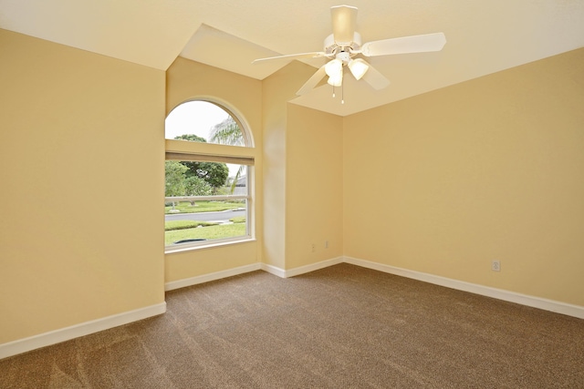 carpeted spare room featuring vaulted ceiling and ceiling fan