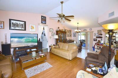 living room with wood-type flooring, ceiling fan with notable chandelier, and lofted ceiling