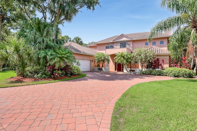 mediterranean / spanish house with a balcony, a garage, and a front lawn