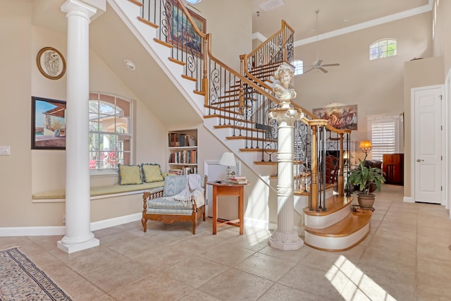 staircase with plenty of natural light, a high ceiling, and decorative columns