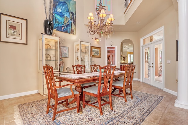 tiled dining room featuring french doors, a towering ceiling, and a chandelier