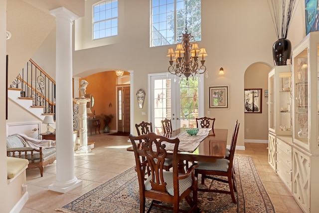 tiled dining space featuring ornate columns, french doors, a high ceiling, and a chandelier