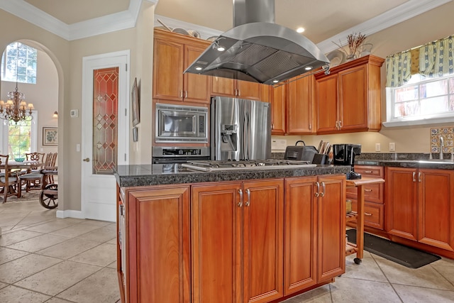 kitchen with island exhaust hood, ornamental molding, stainless steel appliances, an inviting chandelier, and a kitchen island