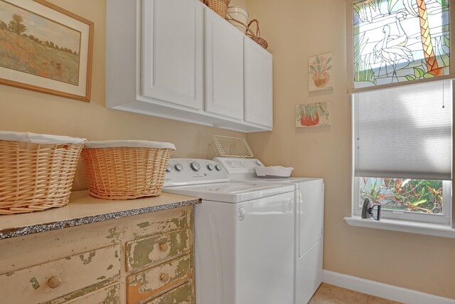 laundry room with washing machine and dryer, light tile patterned floors, and cabinets