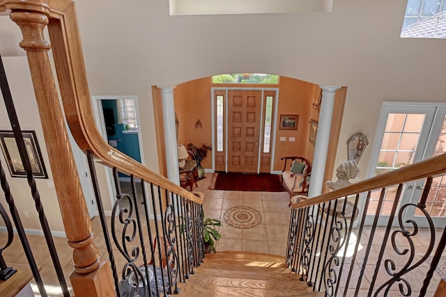 entrance foyer with a high ceiling, decorative columns, and tile patterned floors