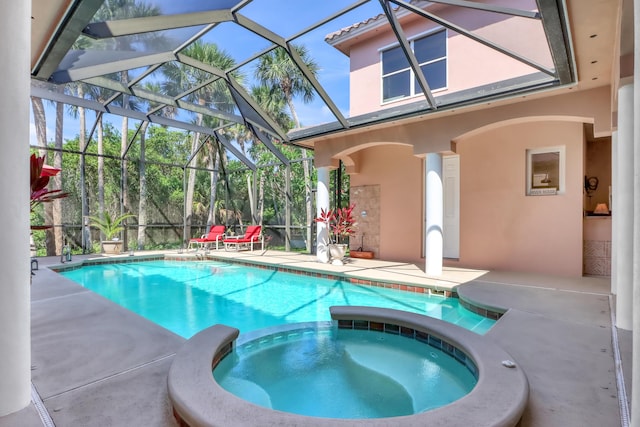 view of swimming pool featuring glass enclosure, an in ground hot tub, and a patio