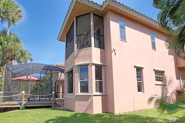 view of side of property with a lawn and a lanai