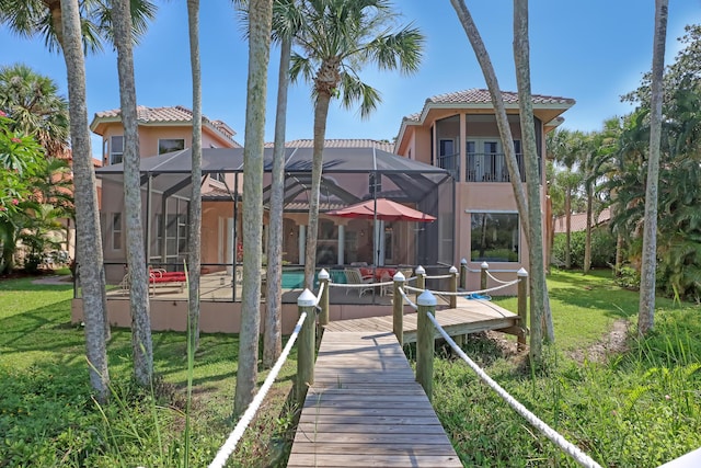 rear view of property featuring a lanai and a lawn