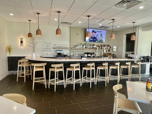 bar with pendant lighting and a paneled ceiling