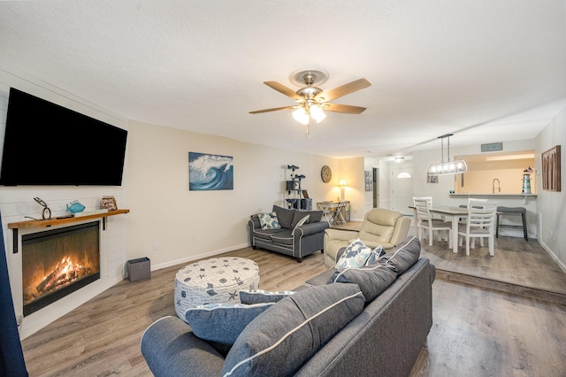 living room with ceiling fan, light hardwood / wood-style flooring, and a textured ceiling