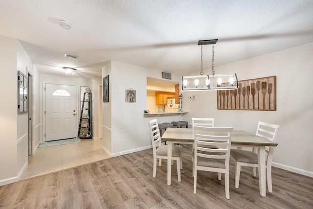 dining area with a textured ceiling and light hardwood / wood-style flooring