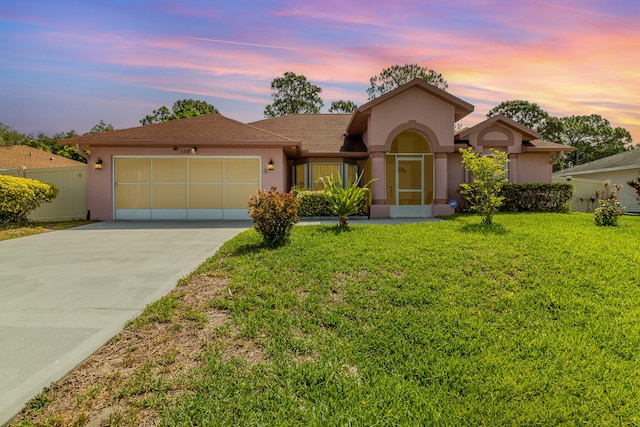 ranch-style home with a garage and a lawn