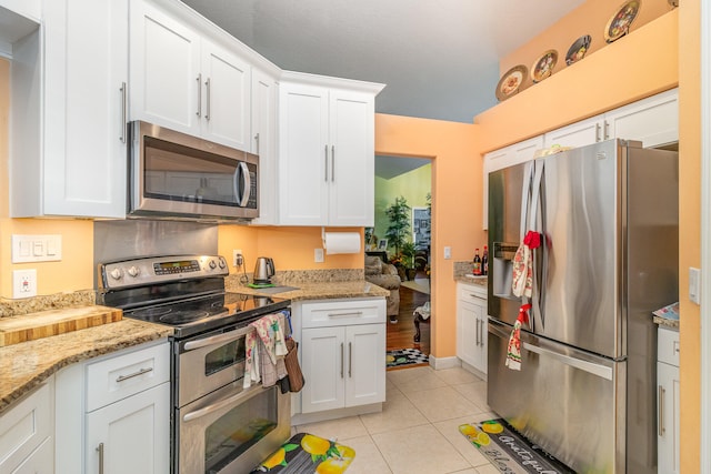 kitchen featuring white cabinets, appliances with stainless steel finishes, light stone countertops, and light tile flooring