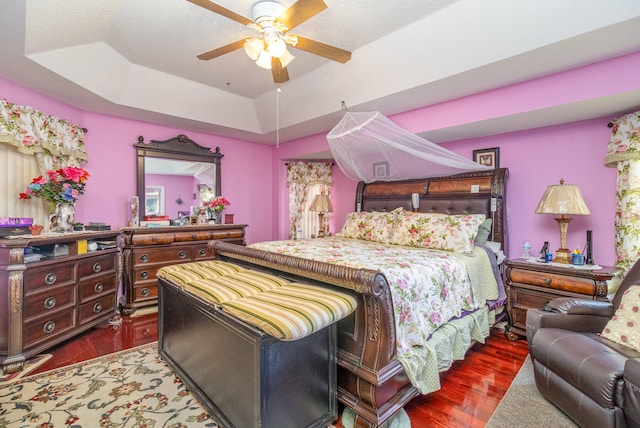 bedroom featuring a tray ceiling, dark wood-type flooring, and ceiling fan