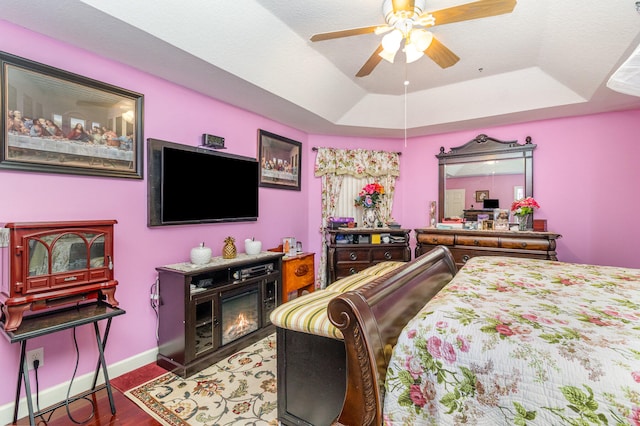 bedroom featuring a tray ceiling, wood-type flooring, and ceiling fan