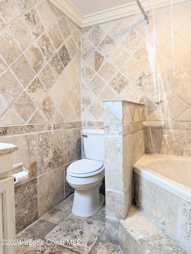 bathroom with toilet, a bathtub, ornamental molding, and tile walls