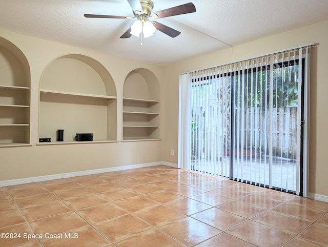 spare room featuring built in shelves, a textured ceiling, tile patterned floors, and ceiling fan