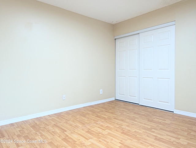 unfurnished bedroom with light wood-type flooring and a closet