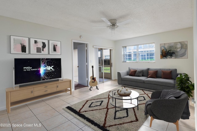 living room with ceiling fan, light tile patterned floors, and a textured ceiling