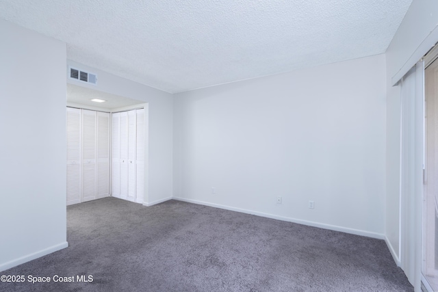 unfurnished bedroom with dark colored carpet, a textured ceiling, and a closet