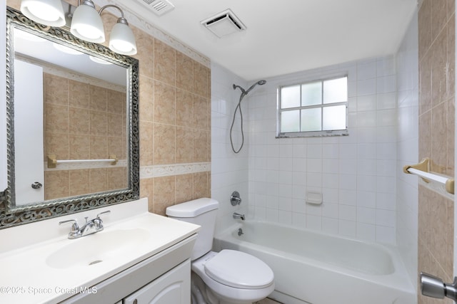 full bathroom with vanity, tiled shower / bath combo, tile walls, and toilet