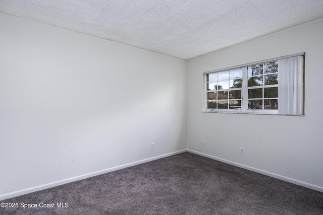 spare room with a textured ceiling and dark colored carpet