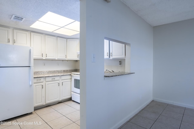 kitchen featuring white cabinetry, light tile patterned floors, and white appliances