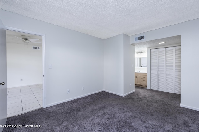 carpeted spare room with a textured ceiling and ceiling fan