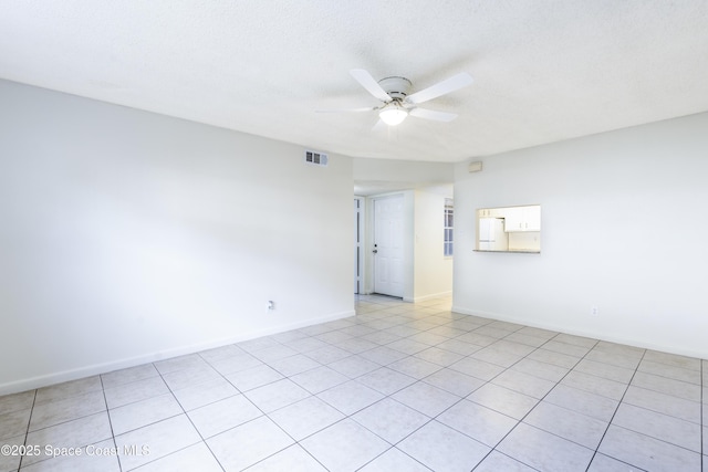 tiled spare room with a textured ceiling and ceiling fan