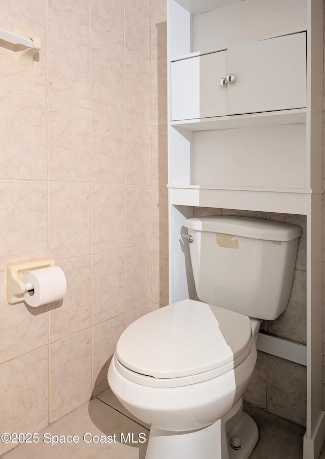 bathroom with tile patterned flooring, toilet, and tile walls