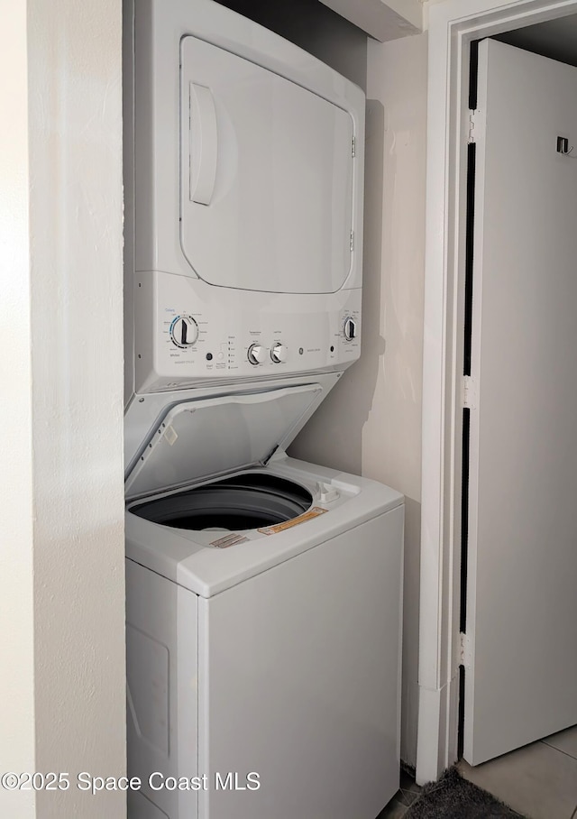 laundry room with tile patterned floors and stacked washer / dryer