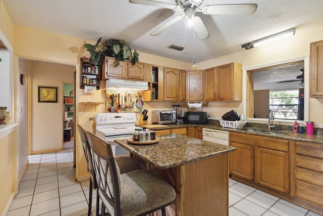 kitchen featuring a textured ceiling, a kitchen breakfast bar, sink, and a center island