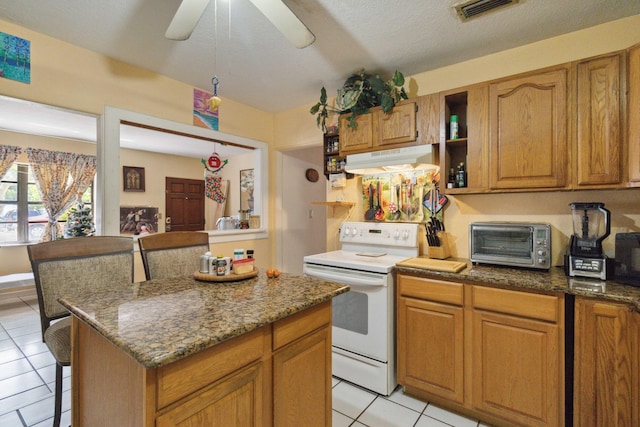 kitchen featuring a kitchen bar, a center island, light tile patterned floors, white electric stove, and dark stone countertops