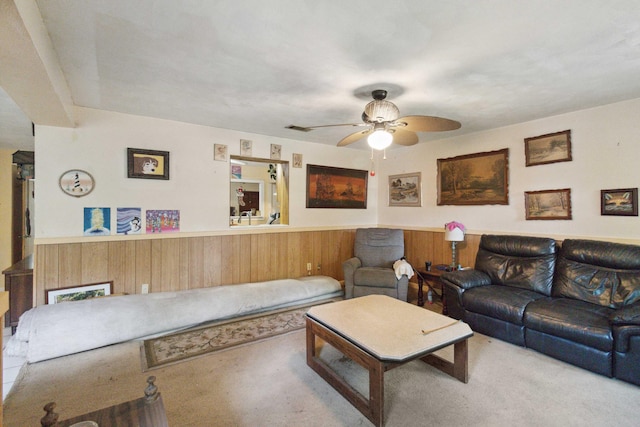 living room with wood walls, ceiling fan, and carpet