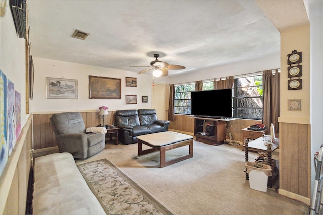 living room with wood walls, ceiling fan, and carpet floors