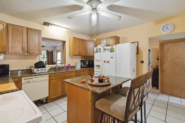 kitchen with a textured ceiling, white appliances, and a kitchen island