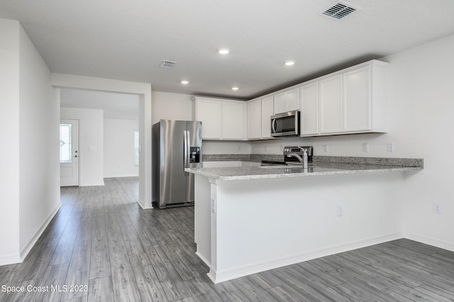 kitchen with kitchen peninsula, wood-type flooring, stainless steel appliances, and white cabinetry