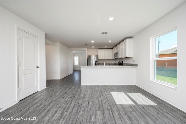 kitchen with light hardwood / wood-style flooring, white cabinetry, stainless steel appliances, a healthy amount of sunlight, and kitchen peninsula