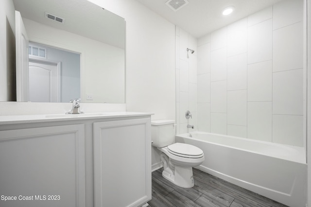 full bathroom with tiled shower / bath, wood-type flooring, vanity, and toilet